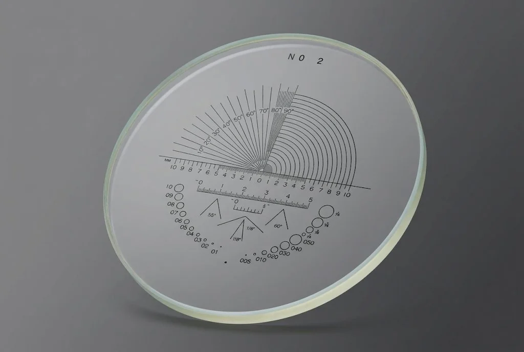 Circular glass comparison reticle with fan gauges, scales and a series of comparison circles etched on the pattern